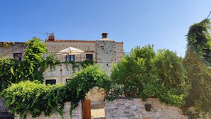 A stone building with a balcony, a wooden gate, and lush greenery. - Villa Laina (Platanias)