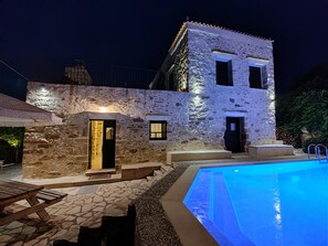 Un bâtiment en pierre doté d’une piscine, caractérisé par une façade en pierre et une structure à deux étages.