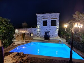 Ein Gebäude aus Stein mit Pool, Treppe und Laterne.