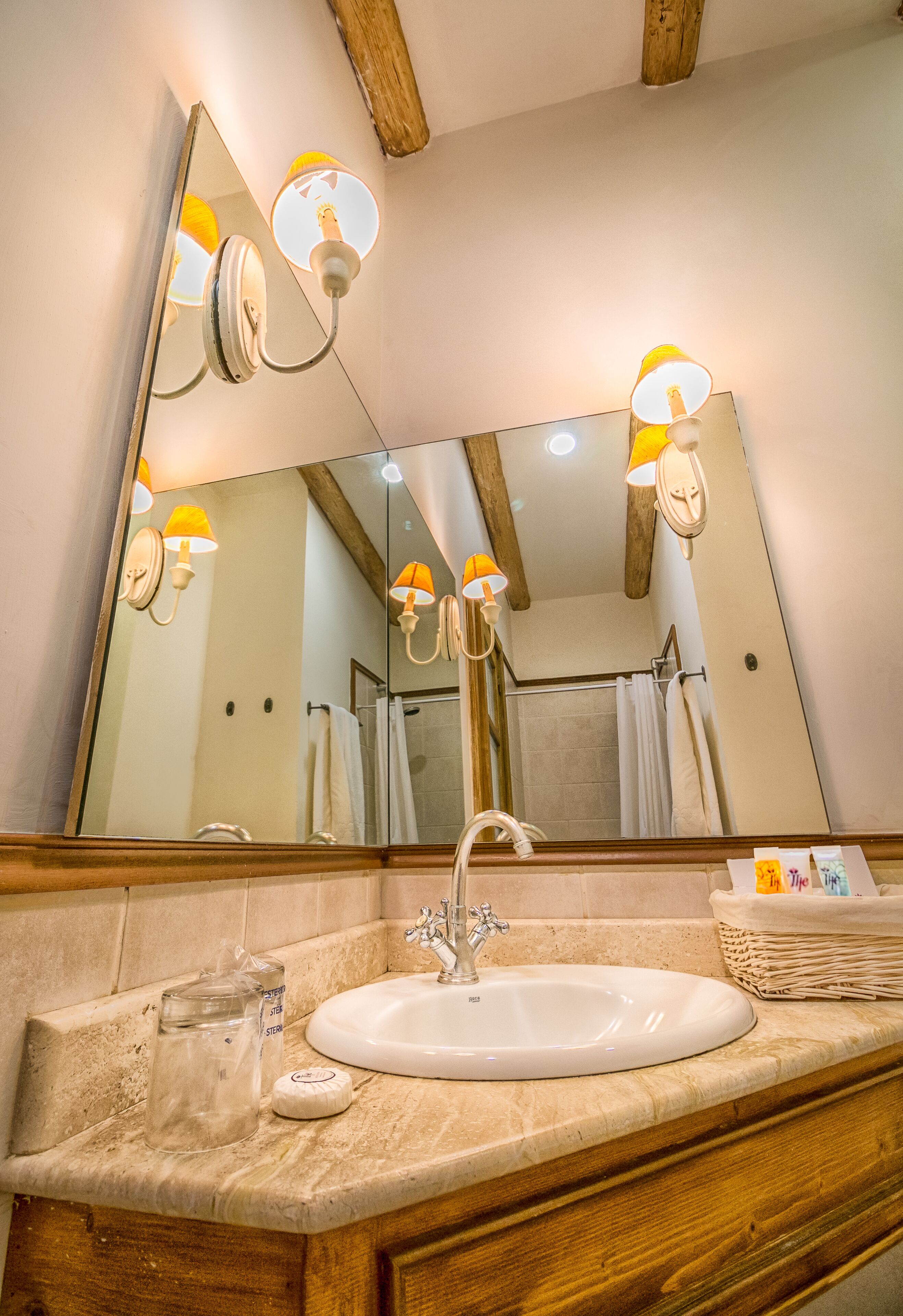 Un bagno con uno specchio grande, un lavandino e due lampade fissate al muro.