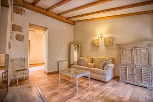 Ein gemütliches Wohnzimmer mit Holzboden, einem weißen Sofa, einem Glastisch und einer Holzkommode.