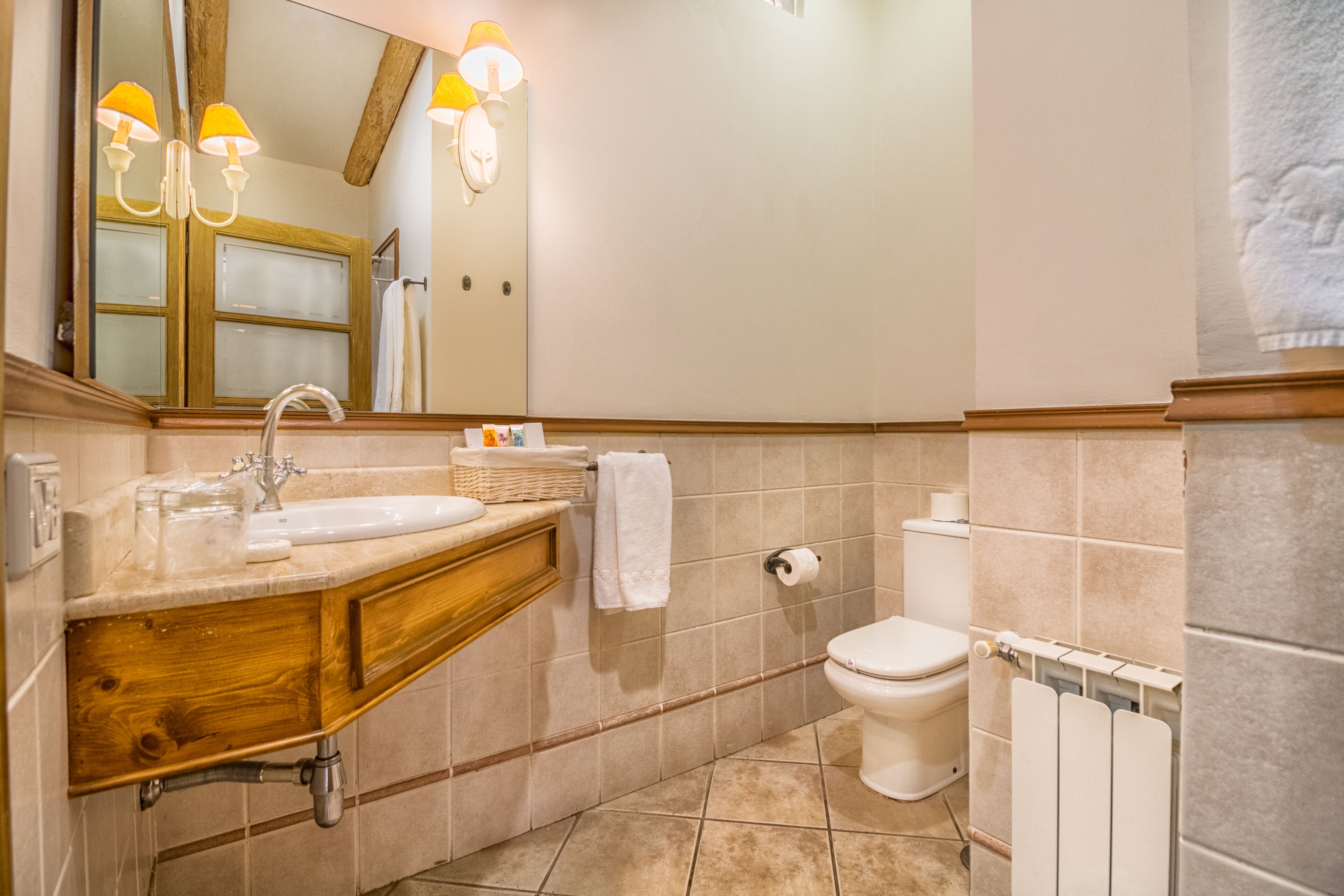 Ein Badezimmer mit einem Holzkosmetikschrank, einem Waschbecken, einem Spiegel, einer Toilette und einem Handtuchhalter.