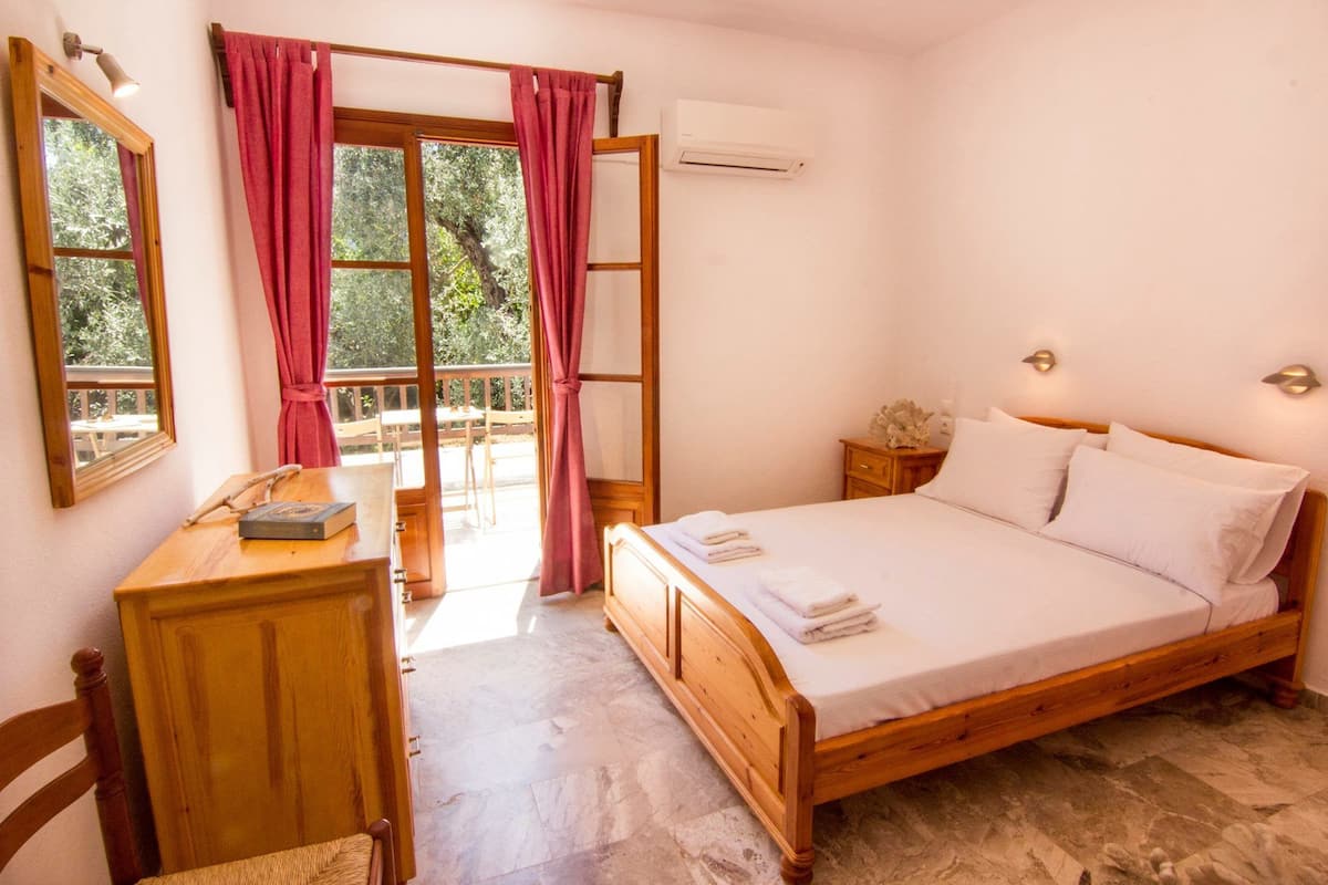 Une chambre Ă coucher avec un lit en bois, un bureau avec un tĂ©lĂ©phone et une fenĂȘtre avec des rideaux.