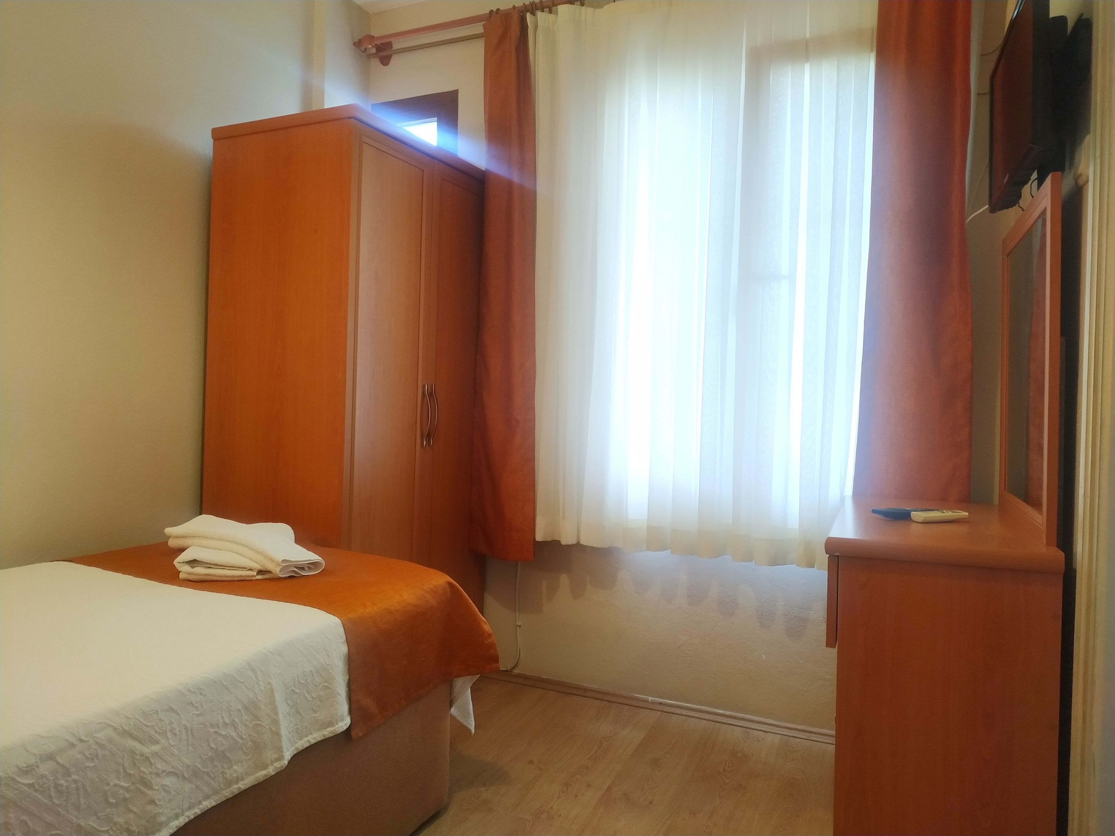 A bedroom with a bed, a wardrobe, and a window with curtains.