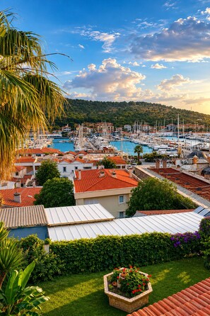 A marina with boats, a hill in the background, and residential buildings with red roofs. - Yalcin Hotel (Cesme)