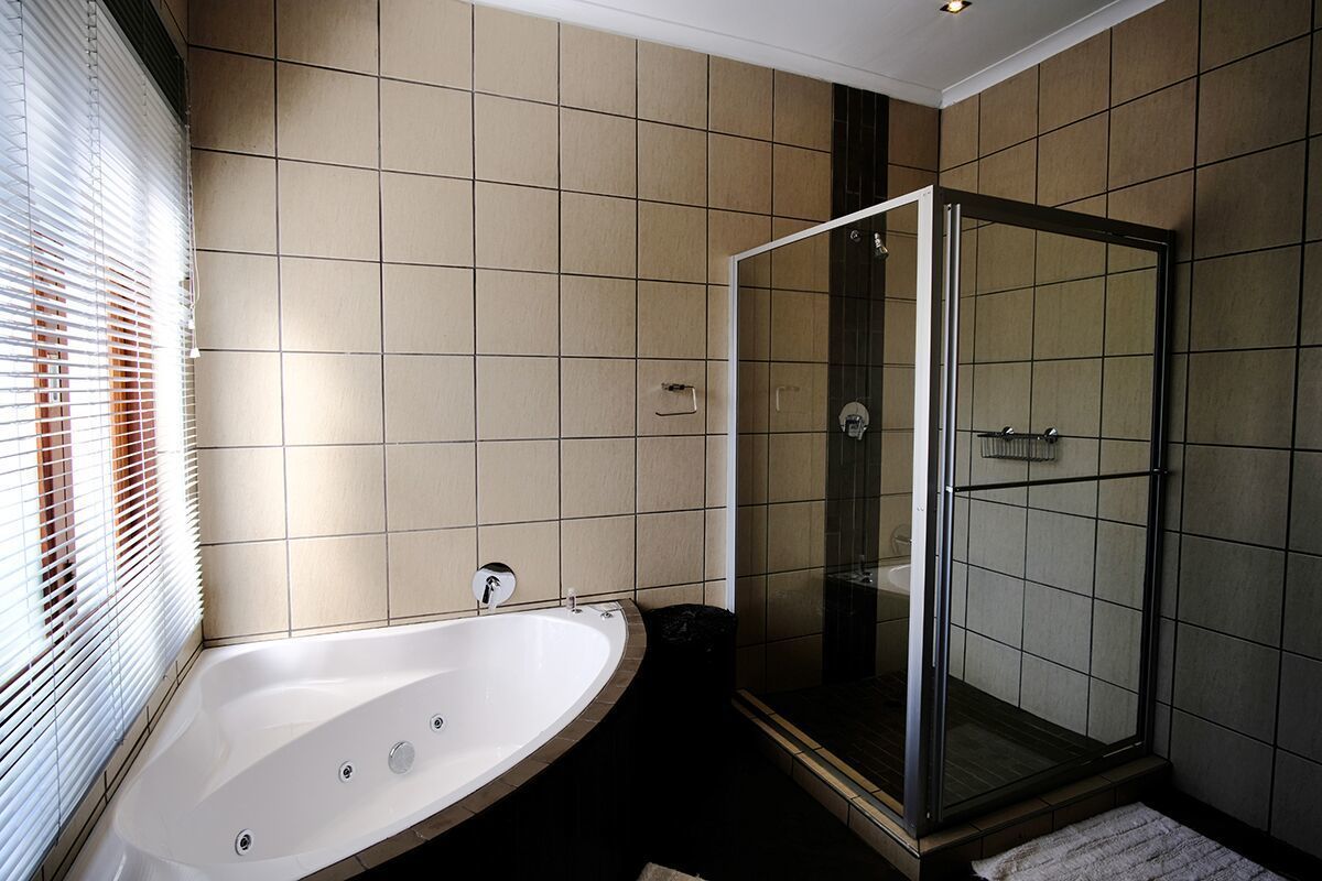 Un baño moderno con una bañera independiente, ducha con mampara de vidrio y paredes con azulejos color beige.