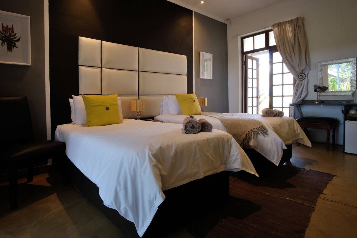 Een hotelkamer met twee bedden, een bureau en een raam met gordijnen.