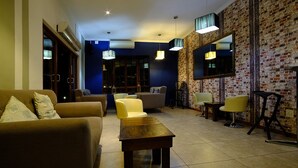 A modern living room with a sofa, armchairs, a coffee table, and a brick-patterned wall. - Cu Boutique Guest House (Phalaborwa)