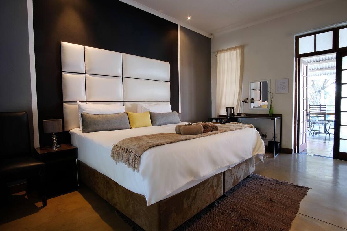 Een moderne slaapkamer met een groot bed, een nachtkastje, een bureau en uitzicht op de omgeving.