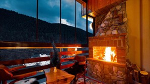 A cozy room with a stone fireplace, a large window overlooking a snowy landscape, and a rustic wooden bench. - Abant Aden Boutique Hotel & Spa (Bolu)