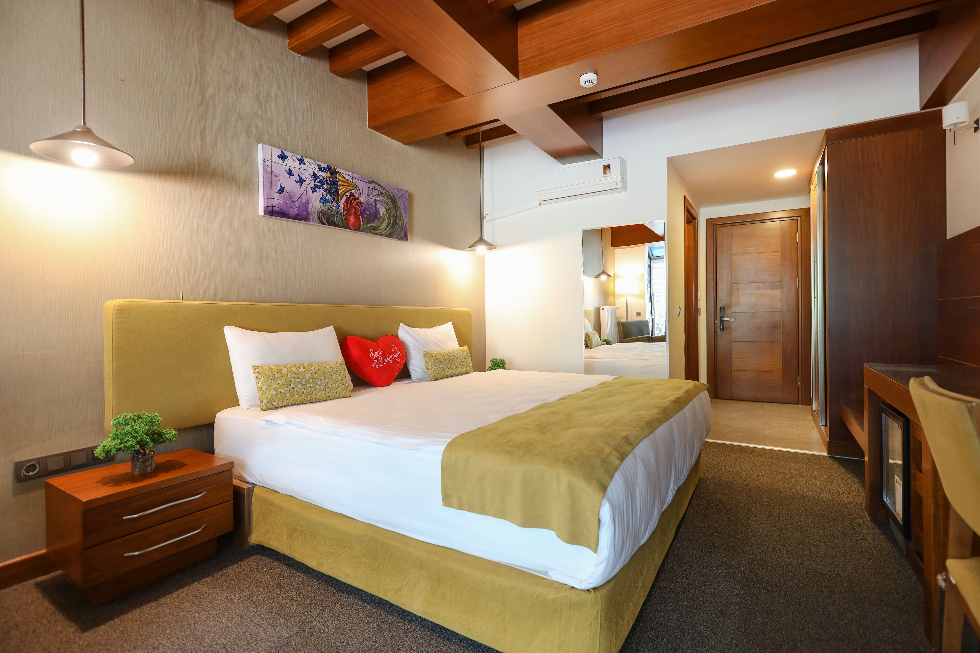A hotel room with a large bed, bedside tables, a desk, and a mirror.
