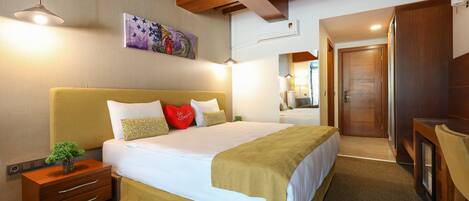 A hotel room with a large bed, bedside tables, a desk, and a mirror.