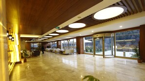 A spacious lobby with a polished marble floor, wooden ceiling panels, and large windows offering a view of the outdoors. - Abant Aden Boutique Hotel & Spa (Bolu)