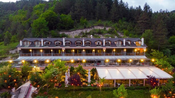 A large, multi-story building with a row of windows on the upper level, surrounded by lush greenery and a hillside backdrop. - Abant Aden Boutique Hotel & Spa (Bolu)