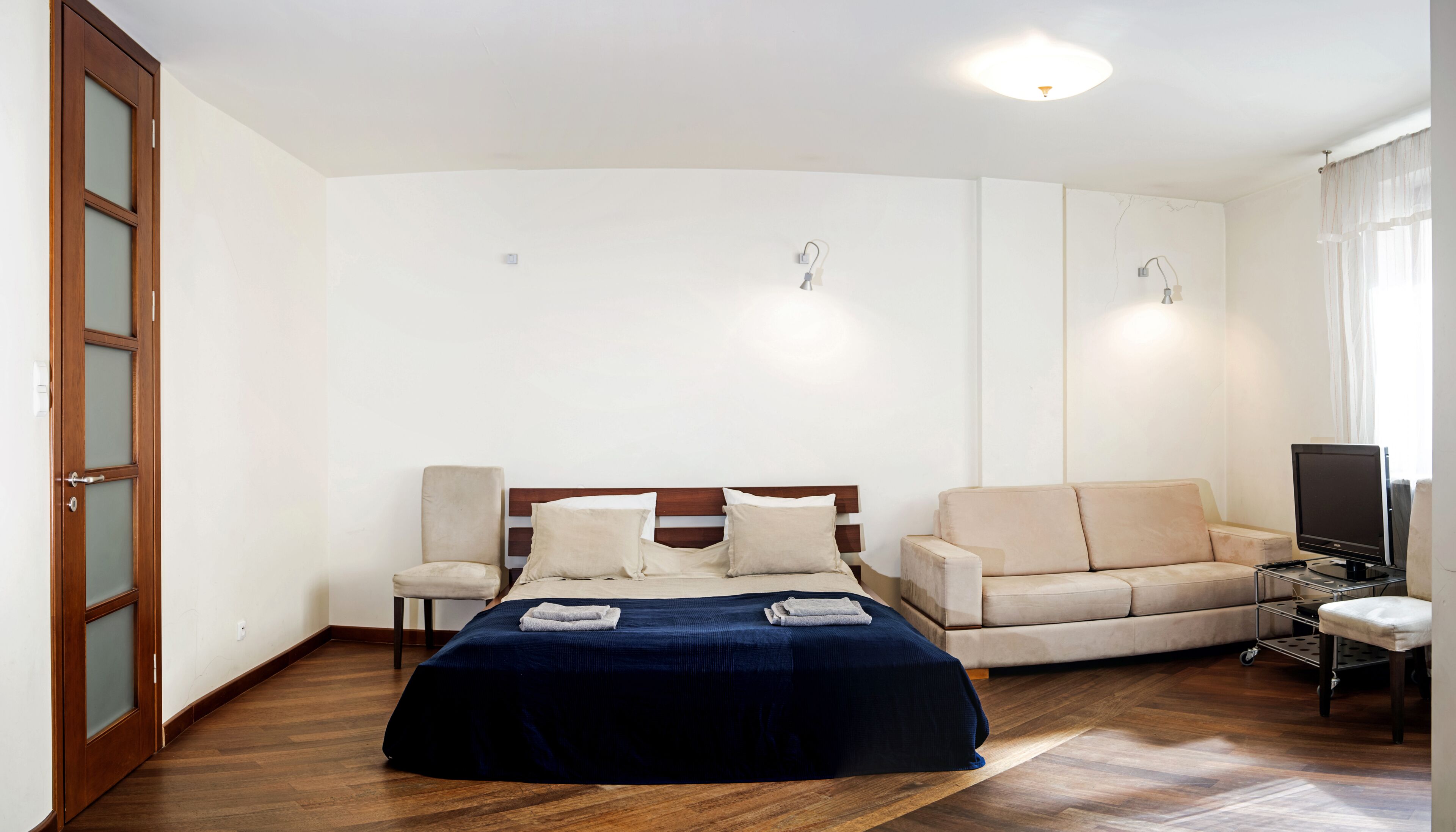 A bedroom with a bed, a sofa, a TV, and a desk.