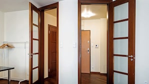 A hotel room with a wooden floor, a bed with a blue blanket, and a wardrobe with a mirror. - Szucha Apartments (Warsaw)