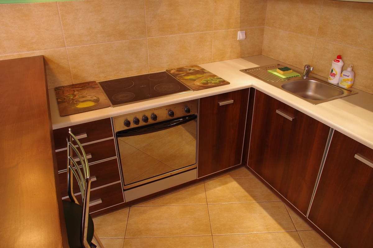 A kitchen with a stove, oven, sink, and wooden cabinets.