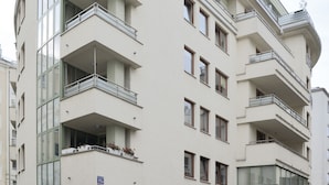 A multi-story building with balconies, a sign indicating 'Szuha Residence', and cars parked in front. - Szucha Apartments (Warsaw)