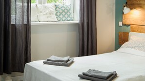 A neatly made bed with pillows, a bedside lamp, and a window with curtains. - Szucha Apartments (Warsaw)