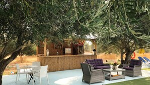 Un área de bar al aire libre con mobiliario de mimbre y una barra de madera.