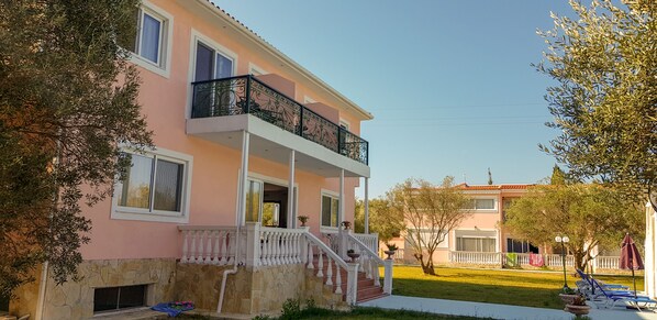 A two-story building with a balcony, a stone foundation, and a well-maintained lawn. - Ai - Helis Resort Hotel (Kefalonia)