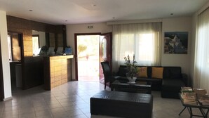 Un hall de hotel con una recepción, un conjunto de sofás, una mesita de centro y un cuadro en la pared.