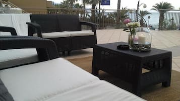 Un espace patio aménagé avec des meubles en osier et une table décorée d’une bougie et de fleurs.
