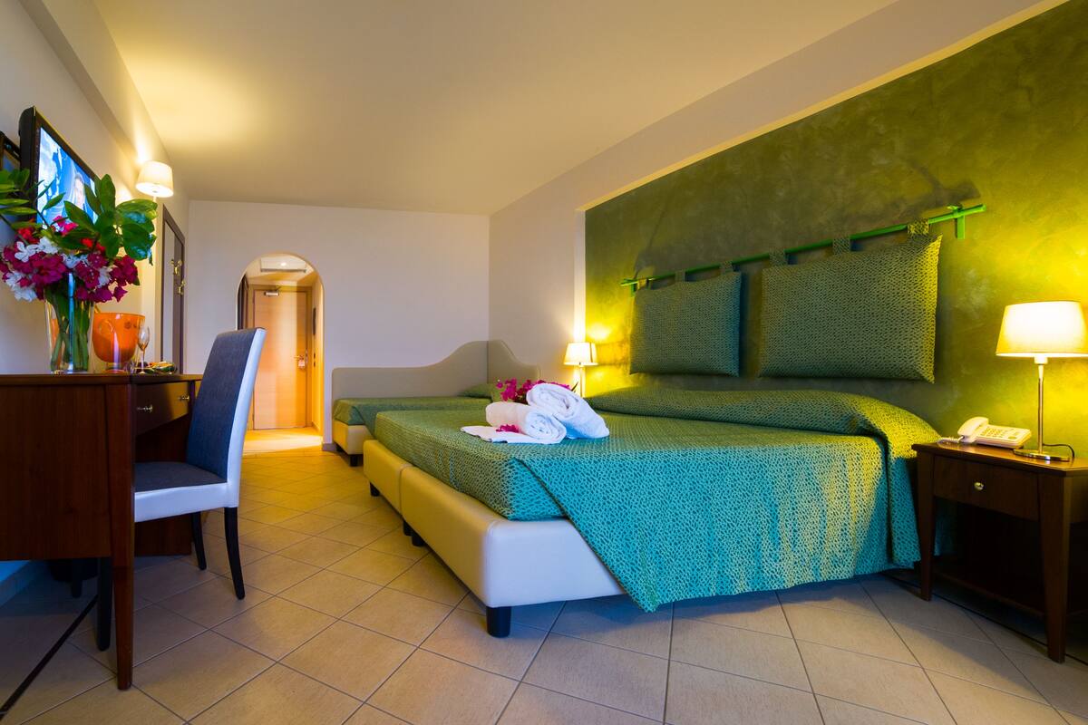 Ein Hotelzimmer mit Bett, Schreibtisch, Stuhl, Nachttisch und Lampe.