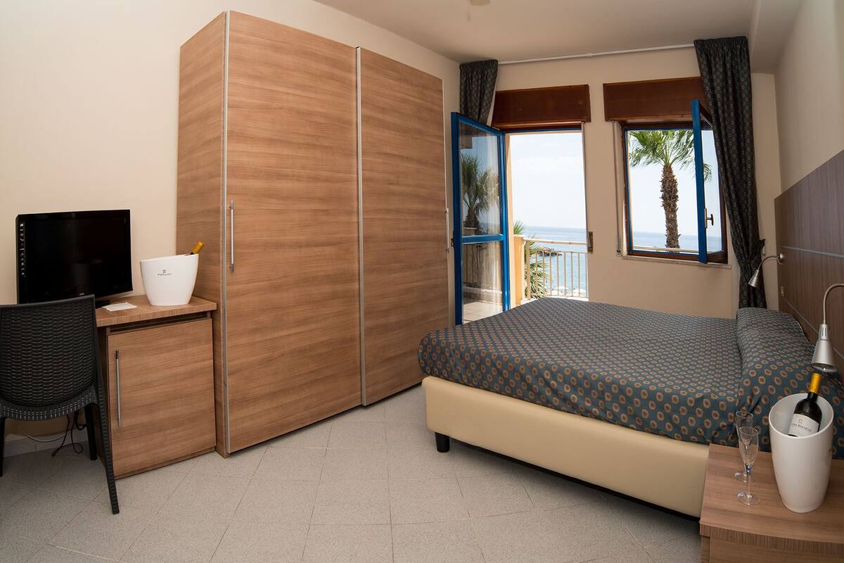 Ein Hotelzimmer mit Bett, Schreibtisch mit Computer, Stuhl, Minibar und Meerblick.