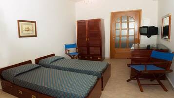 A bedroom with two beds, a desk, a chair, a wardrobe, and a television.