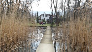 A pathway leading to a white house with a sloped roof, surrounded by tall reeds and trees. - Beta Home Lake House (Sapanca)