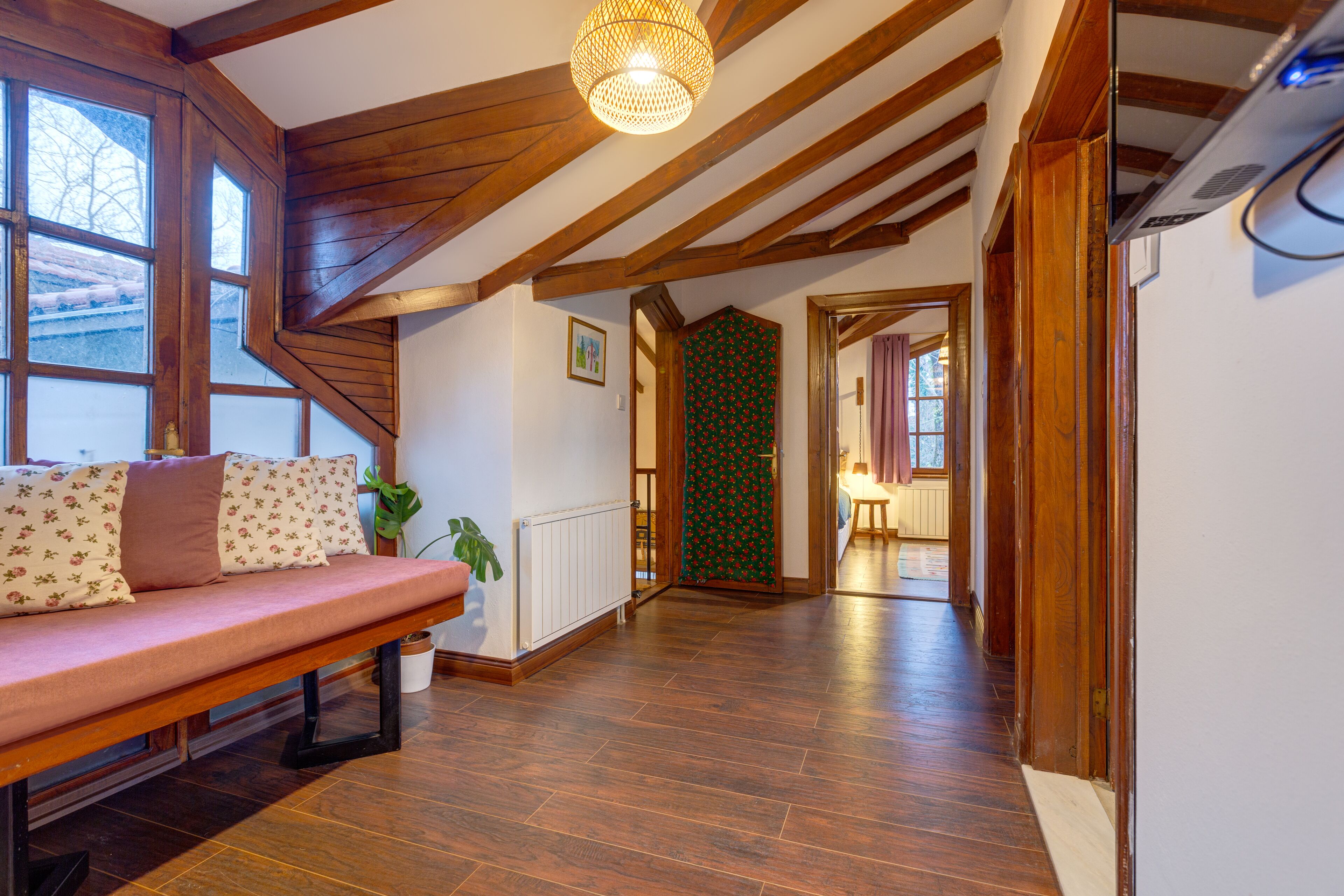 A spacious hallway with wooden floors and a bench with floral cushions.