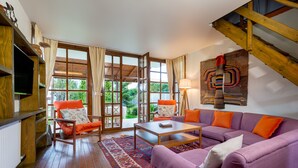 A living room with a purple sofa, orange armchairs, a wooden coffee table, and a large window with curtains. - Beta Home Lake House (Sapanca)