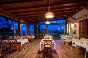 A dining area with tables and chairs, large windows, and a wooden ceiling. - Beta Home Lake House (Sapanca)