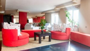 Een moderne woonkamer met rode banken, een zwarte salontafel en een potplant.
