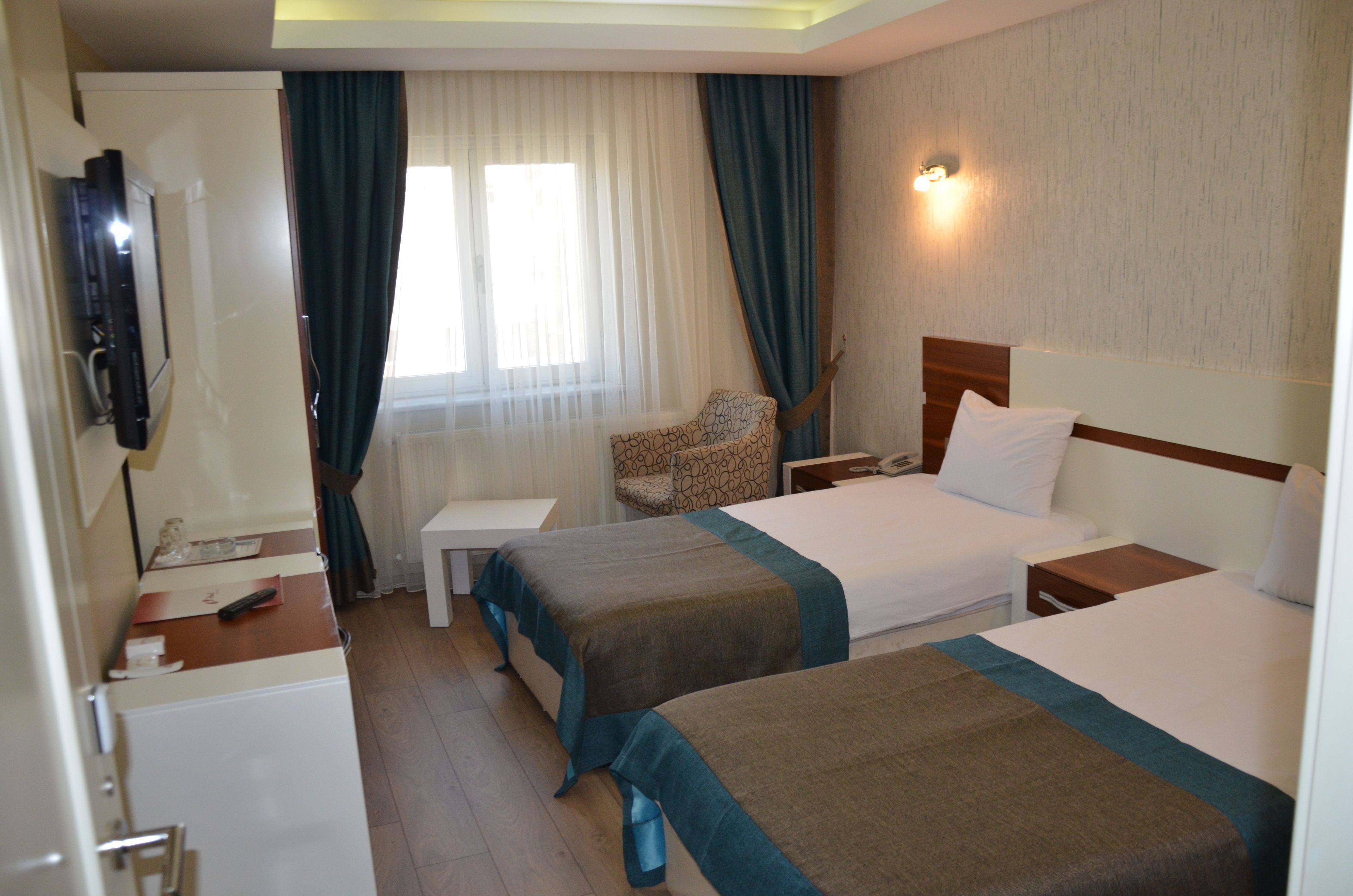 A hotel room with two beds, a TV, a desk, and a chair.