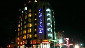 Een hotel met een opvallend neonbord, meerdere verdiepingen en een goed verlichte gevel.