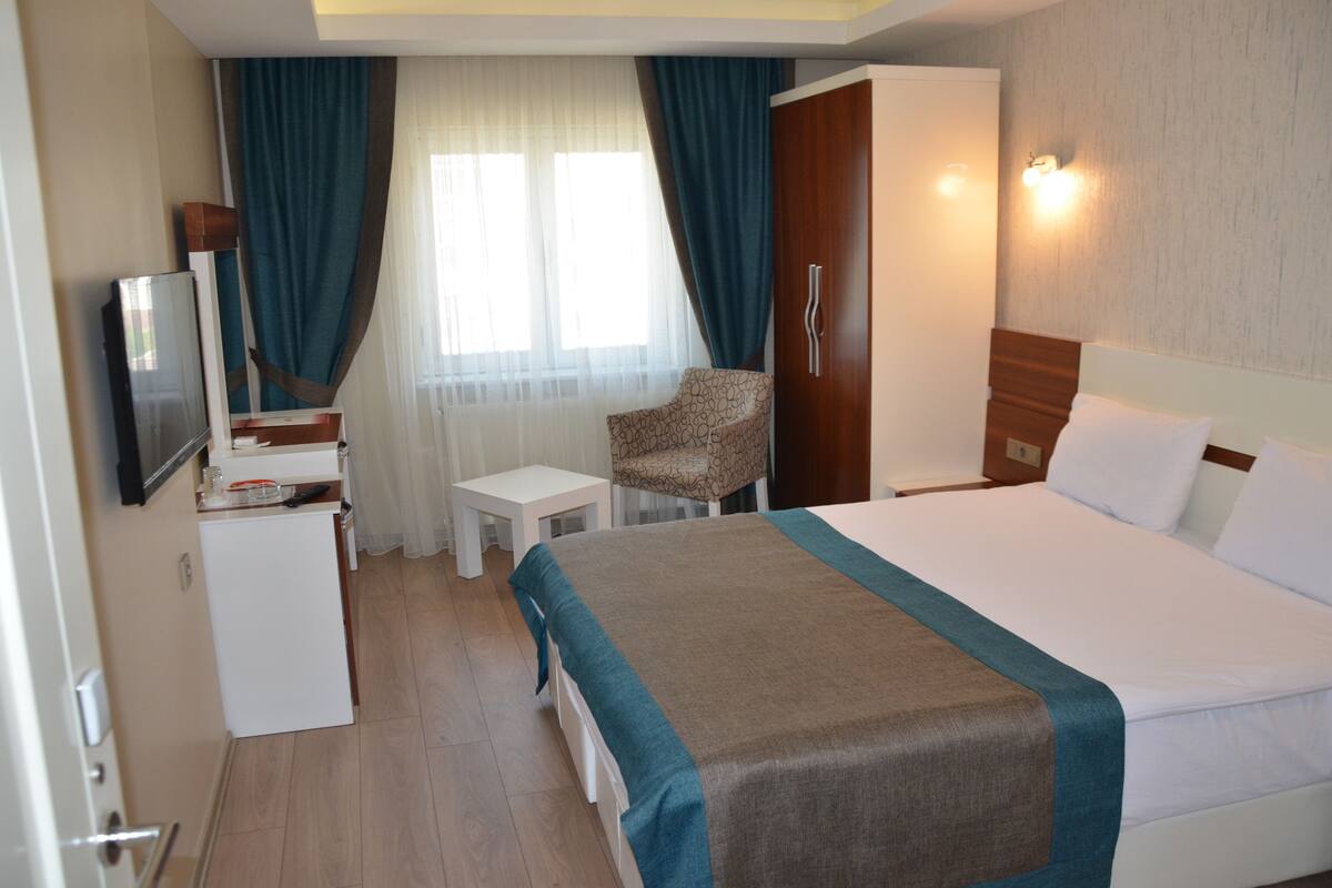 Une chambre d’hôtel équipée d’un lit, d’un bureau, d’une chaise, d’une télévision et d’une armoire.