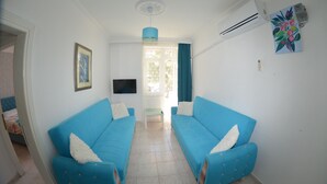 A room with two blue sofas, a television, and a painting on the wall. - Side Apart Hotel (Manavgat)