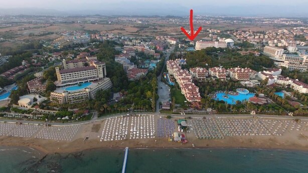 An aerial view of a resort with multiple buildings, a large pool area, and a beach with umbrellas. - Side Apart Hotel (Manavgat)