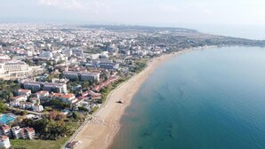An aerial view of a coastal city with a beach, buildings, and a clear blue sea. - Side Apart Hotel (Manavgat)