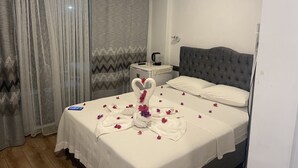 A neatly made bed with a white bedspread and a decorative towel with rose petals. - Side Apart Hotel (Manavgat)