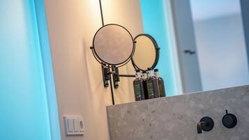 A bathroom with two round mirrors mounted on the wall, a soap dispenser, and a light switch.