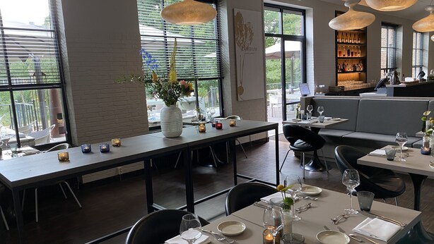 Ein Restaurant mit Essbereich, einer Bar und großen Fenstern mit Blick.