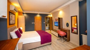 Une chambre d’hôtel comprenant un lit, un bureau, une chaise, une télévision et une salle de bain.