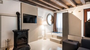 A modern interior with a fireplace, a flat-screen TV, a staircase, and a round window. - MYSWEETPLACE - Fondamenta Moro Apartment (Venice)