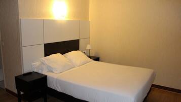 A neatly made bed with white linens in a hotel room.