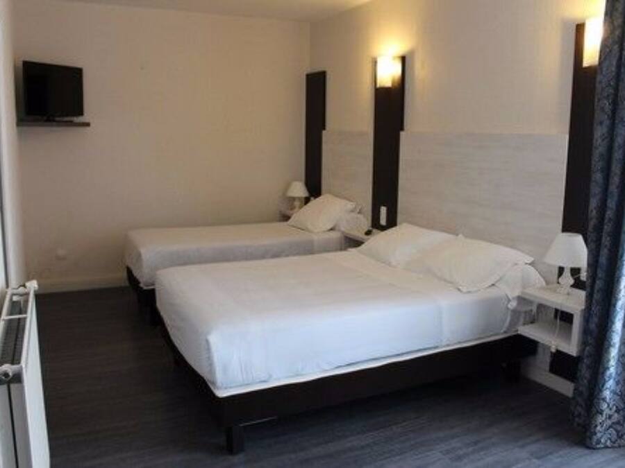 Une chambre d’hôtel avec deux lits, une télévision et une table de chevet avec une lampe.