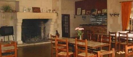 Un comedor con chimenea, sillas de madera y una mesa.