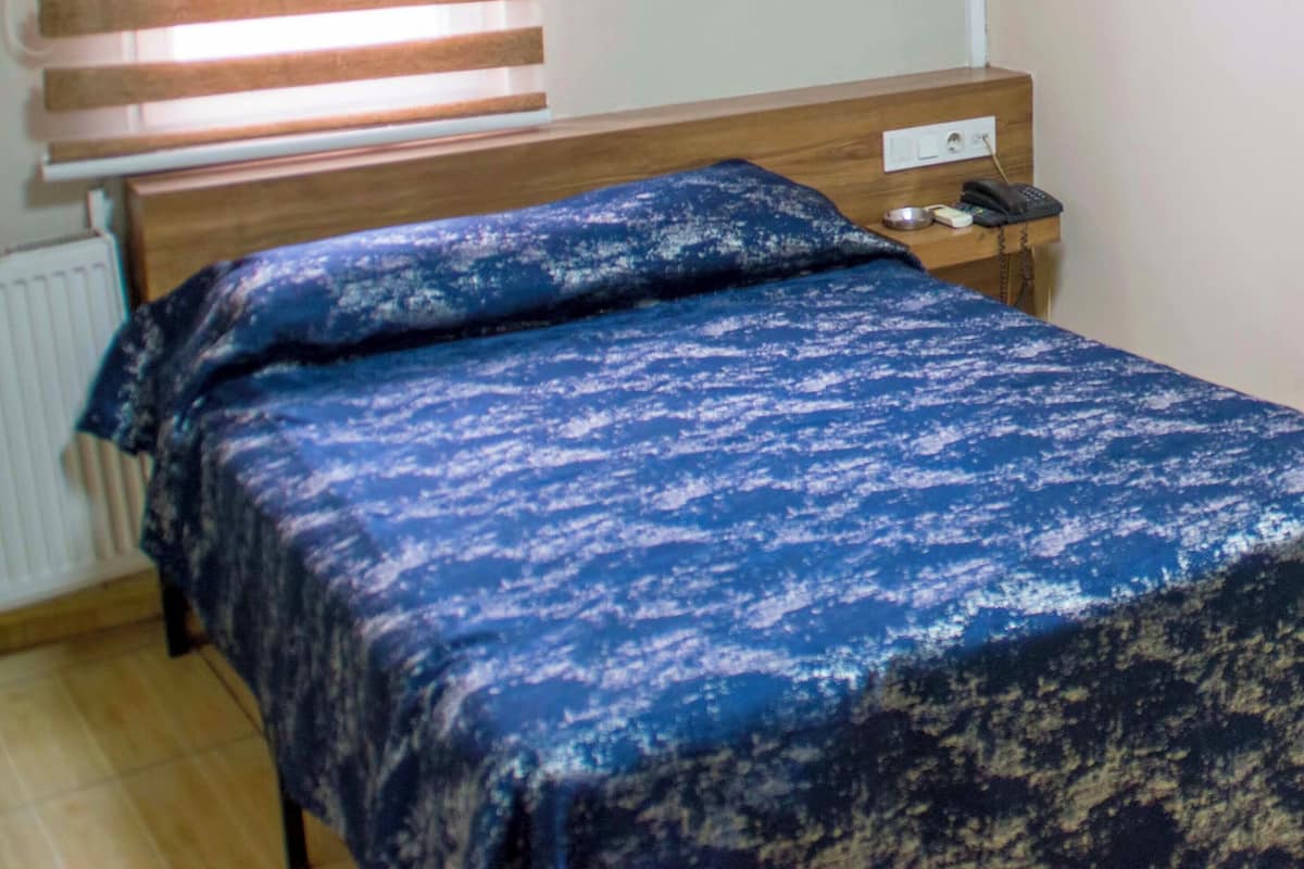 Un dormitorio con una cama, una mesita de noche con un teléfono y un equipo de aire acondicionado en la pared.